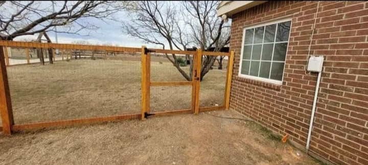 Wooden gate installation next to brick home